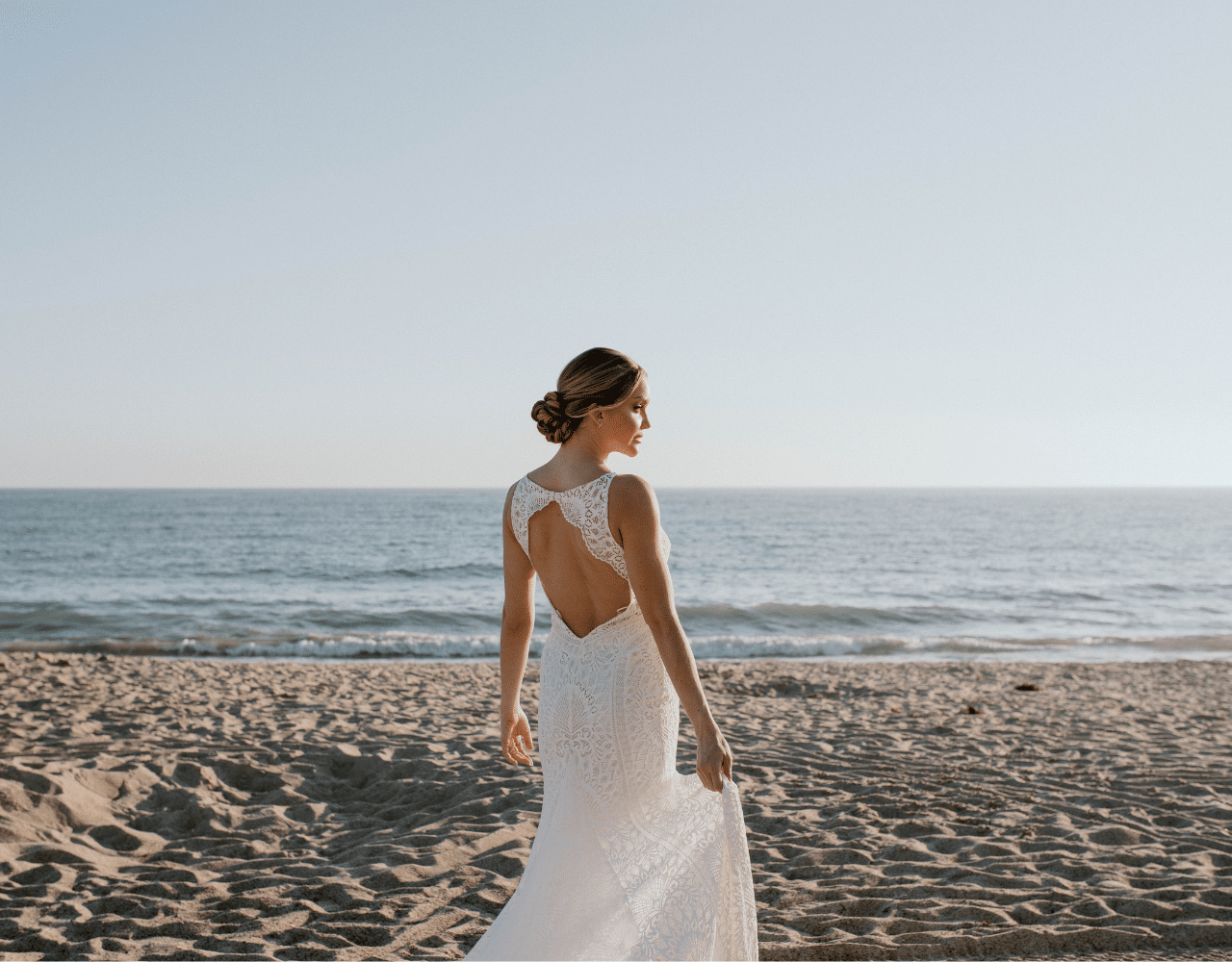 bride at San Clemente beach playing with dress