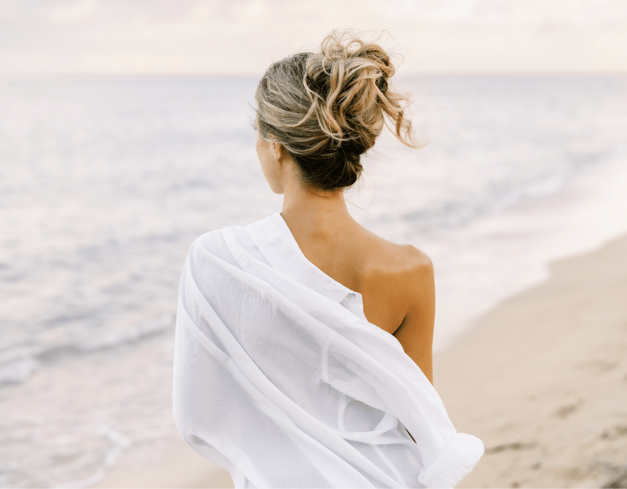 woman on beach with a white shirt and freshly spray tanned skin