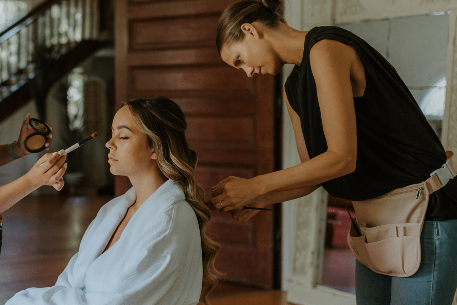 a hair stylist and makeup artist working on a bride